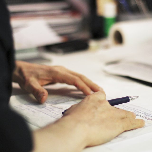 Händer som ritar en byggnad